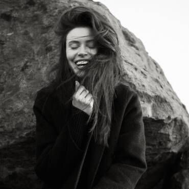 Una fotografía en blanco y negro de una mujer riendo con su cabello ondeando al viento.