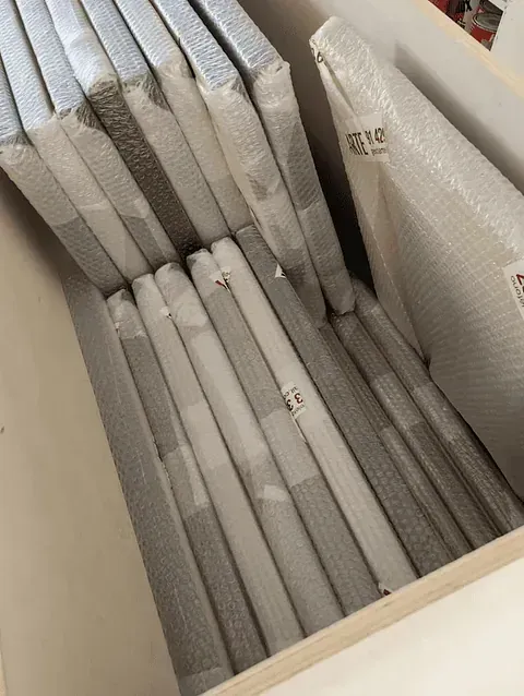 Lienzos envueltos y apilados dentro de una caja blanca, listos para envío o almacenamiento.