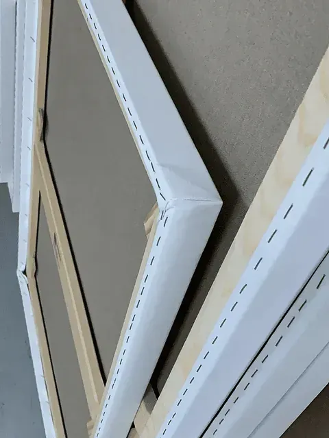 Primer plano de múltiples marcos de lienzo con tela blanca estirada sobre marcos de madera, grapados en los bordes.