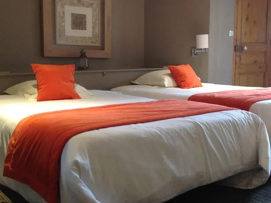 Lits dans un hôtel avec des coussins orange.