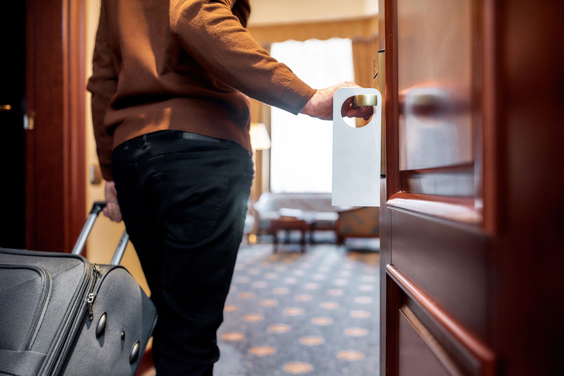 Homme qui rentre dans une chambre d'hôtel avec une valise.