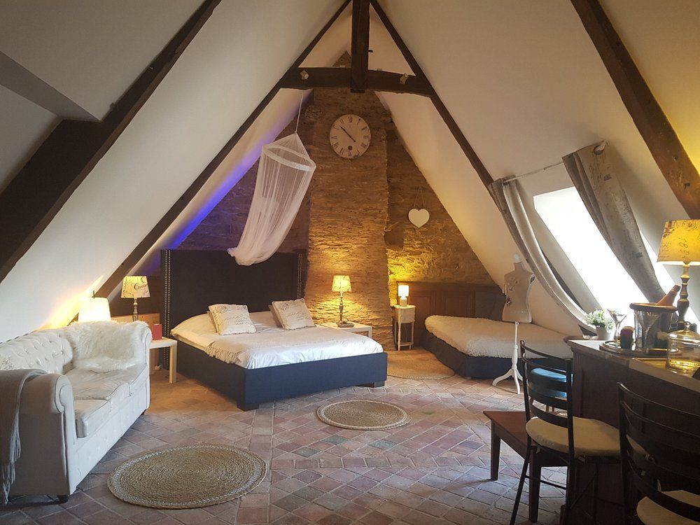 Chambre traditionnelle avec poutres en bois et mur en pierres.