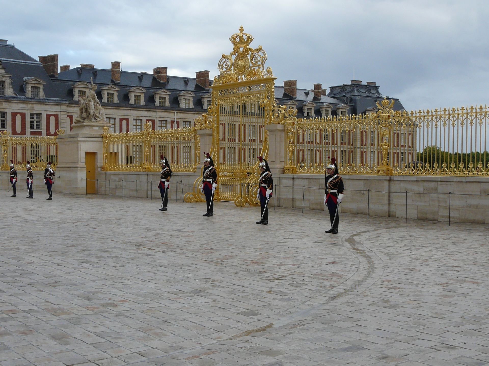 Grille de sécurité dorée, vue sur bâtiment et sur gardiens