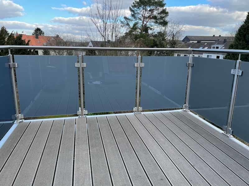 Ein Balkon mit Glasgeländer und Holzterrasse.