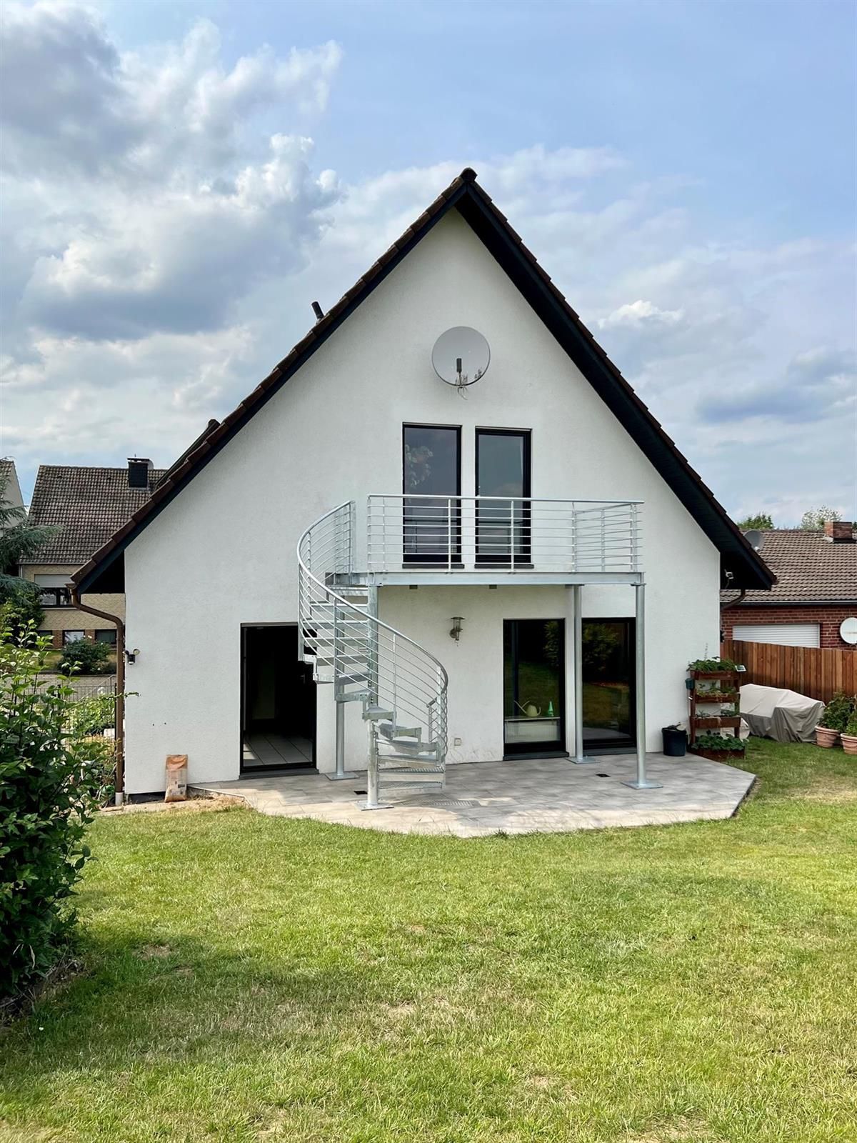 Ein weißes Haus mit einer Wendeltreppe und einem Balkon