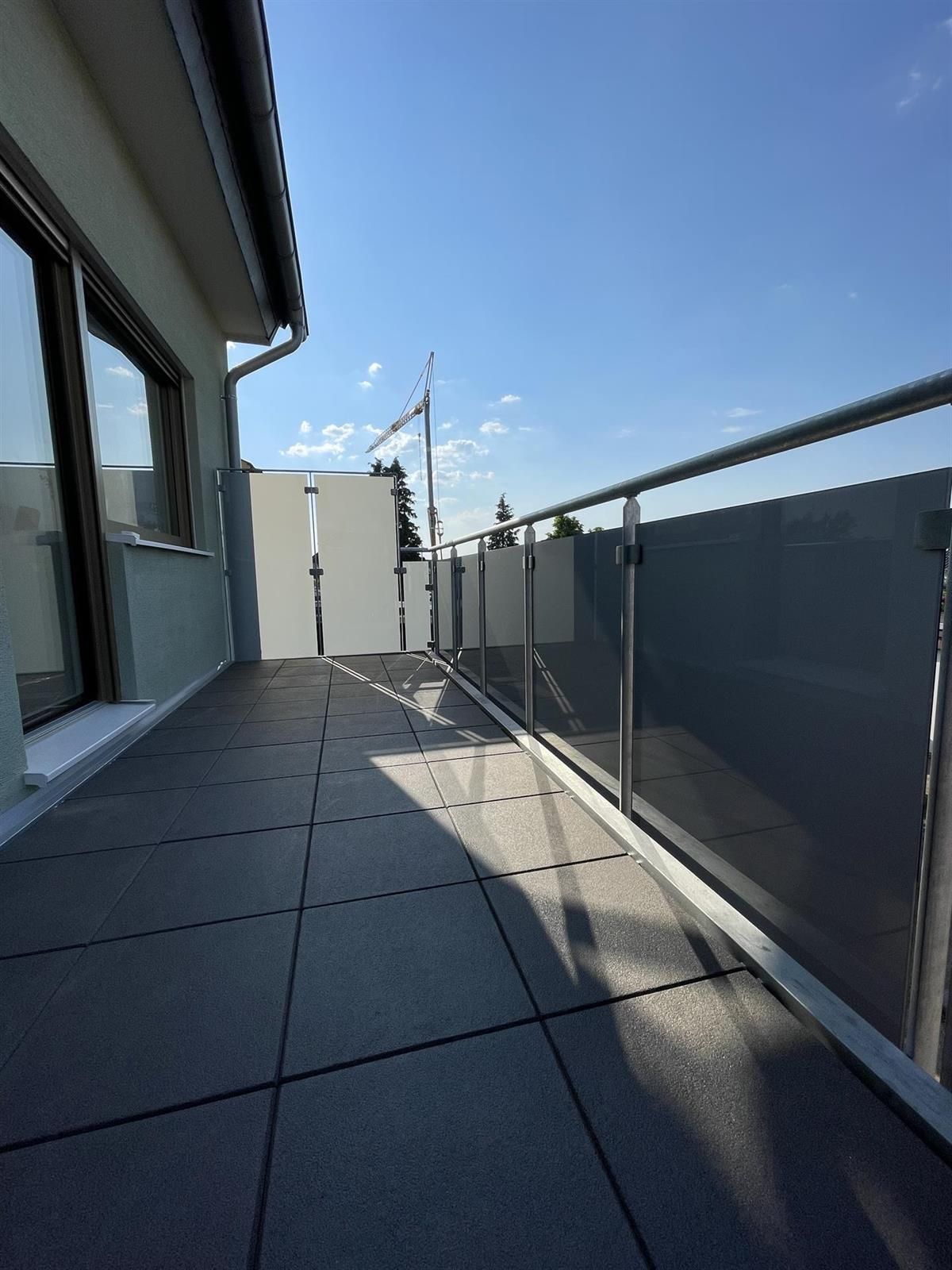 Ein Balkon mit Glasgeländer und blauem Himmel im Hintergrund