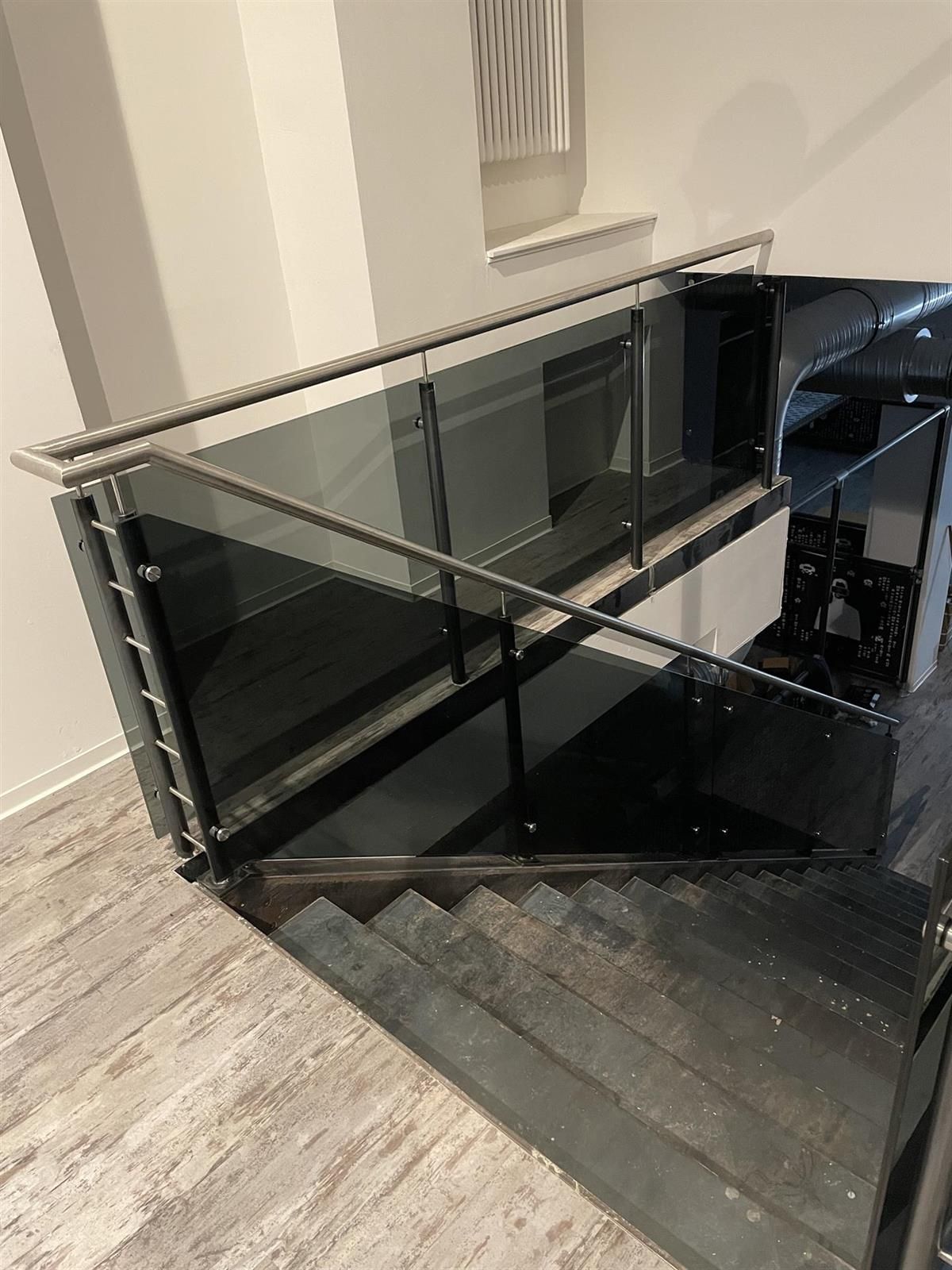 Eine Treppe mit einem Glasgeländer und einem Edelstahlgeländer.