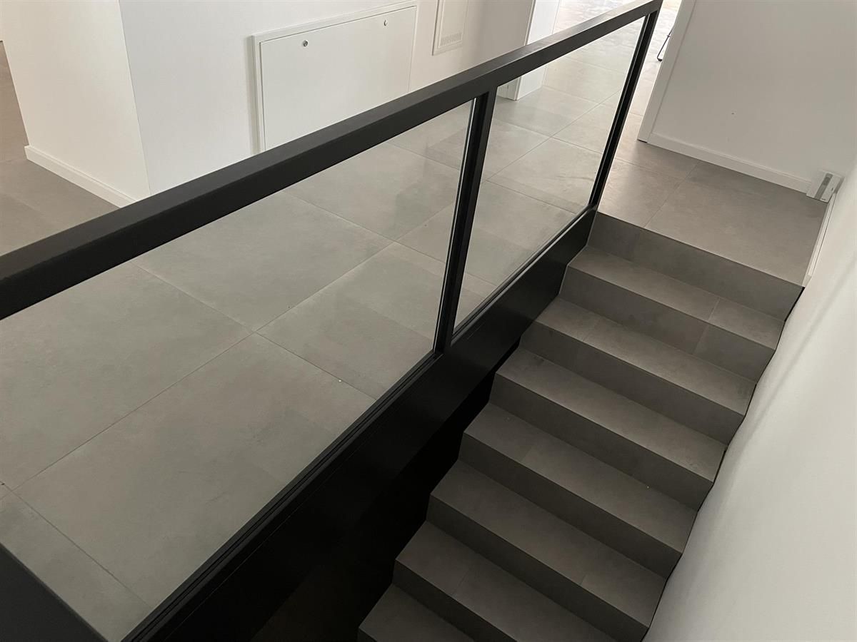 Eine Treppe mit schwarzem Geländer und Glasgeländer