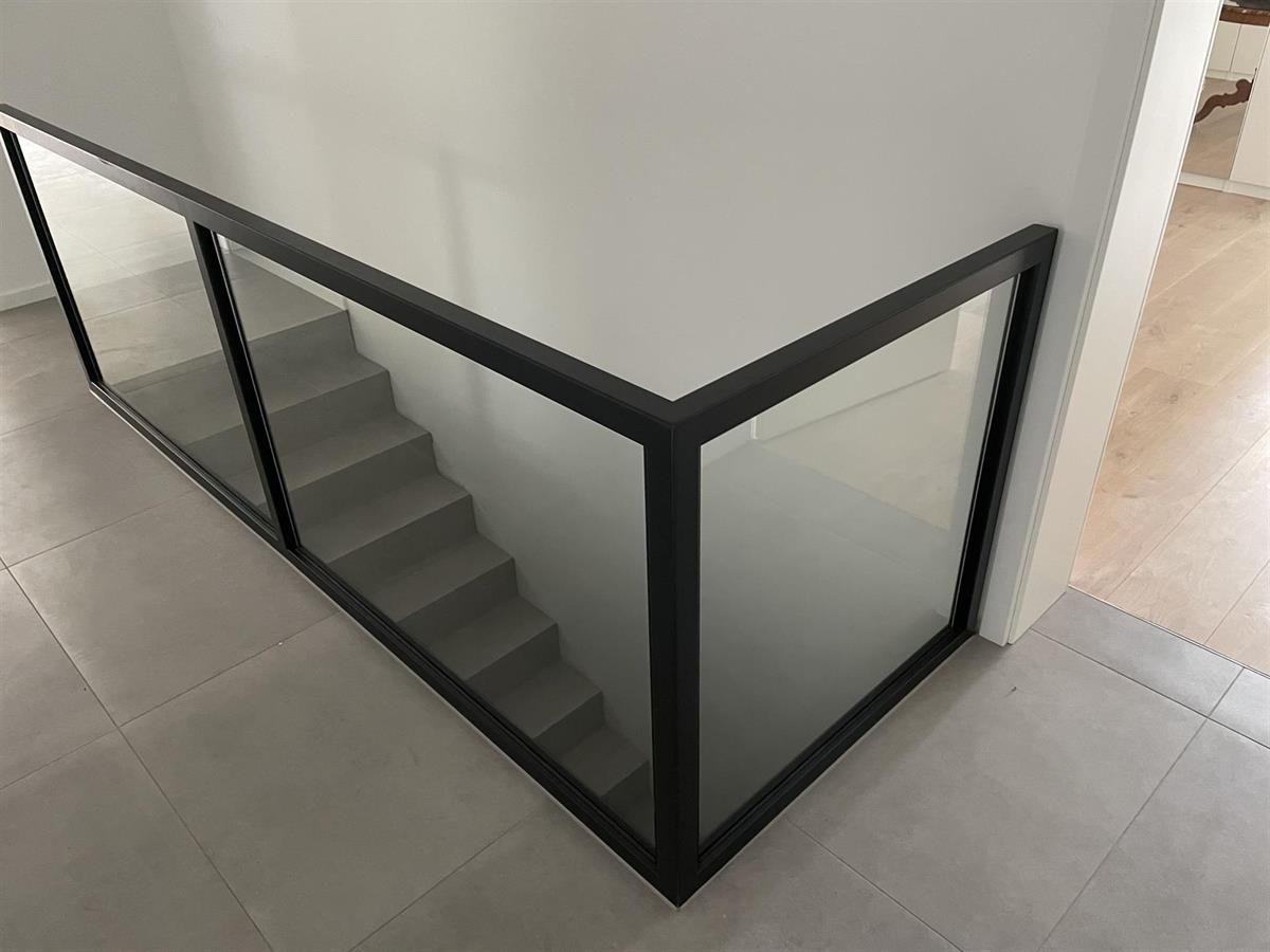 Eine Treppe mit Glasgeländer und schwarzem Rahmen.