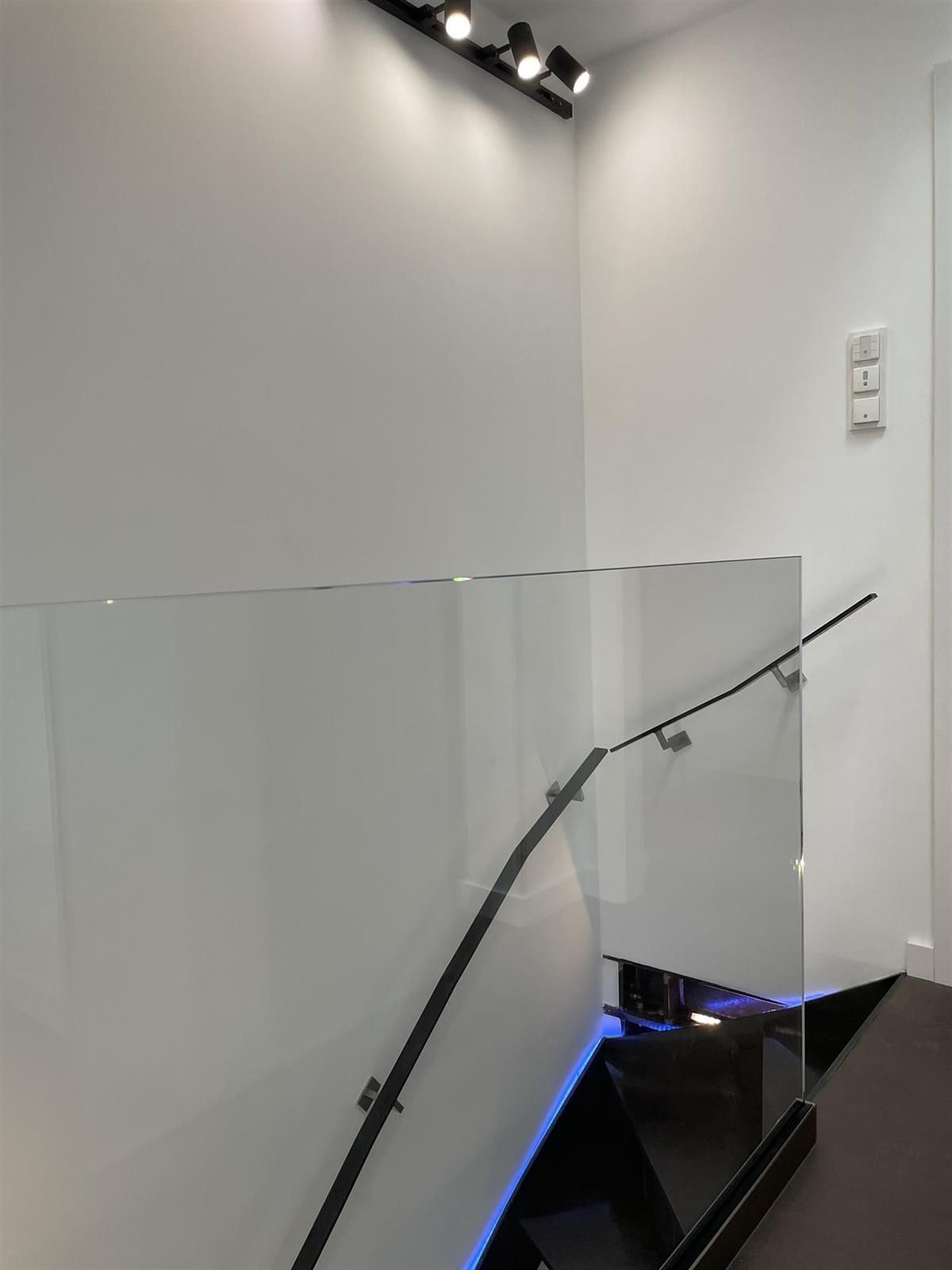 Eine Treppe mit einem Glasgeländer und einem schwarzen Handlauf