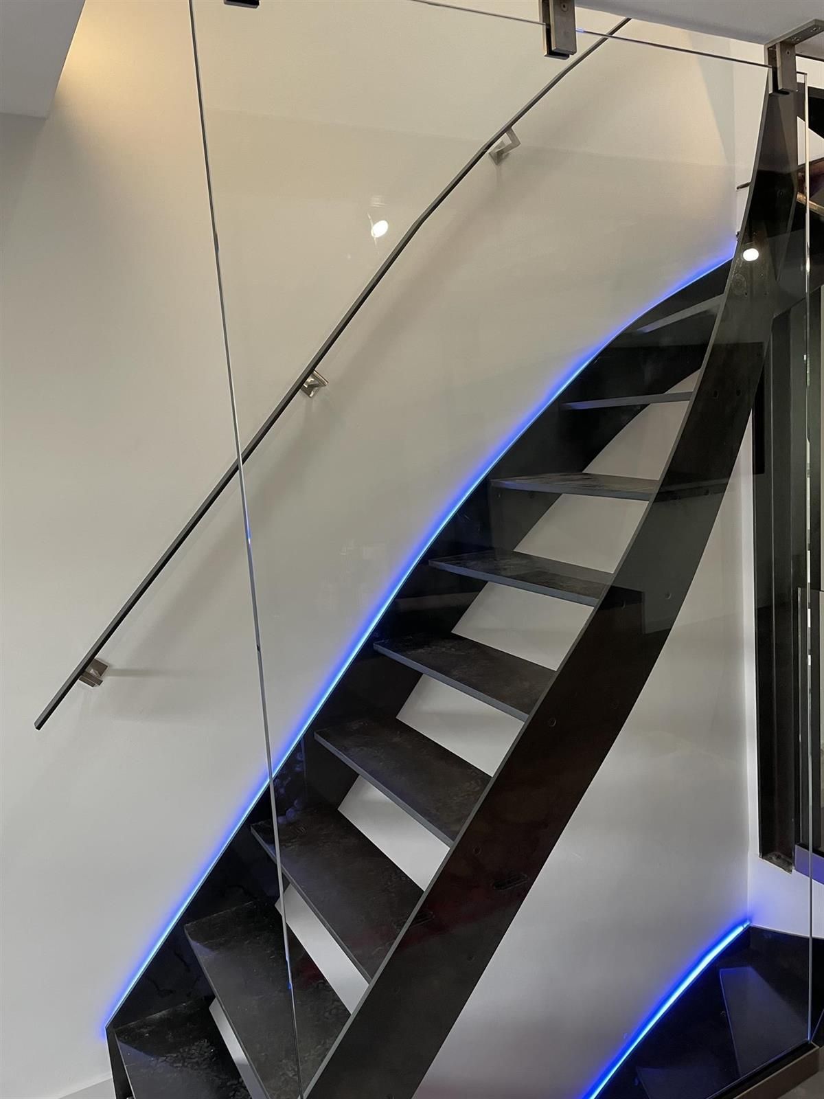 Eine schwarze Treppe mit Glasgeländer und blauen Lichtern