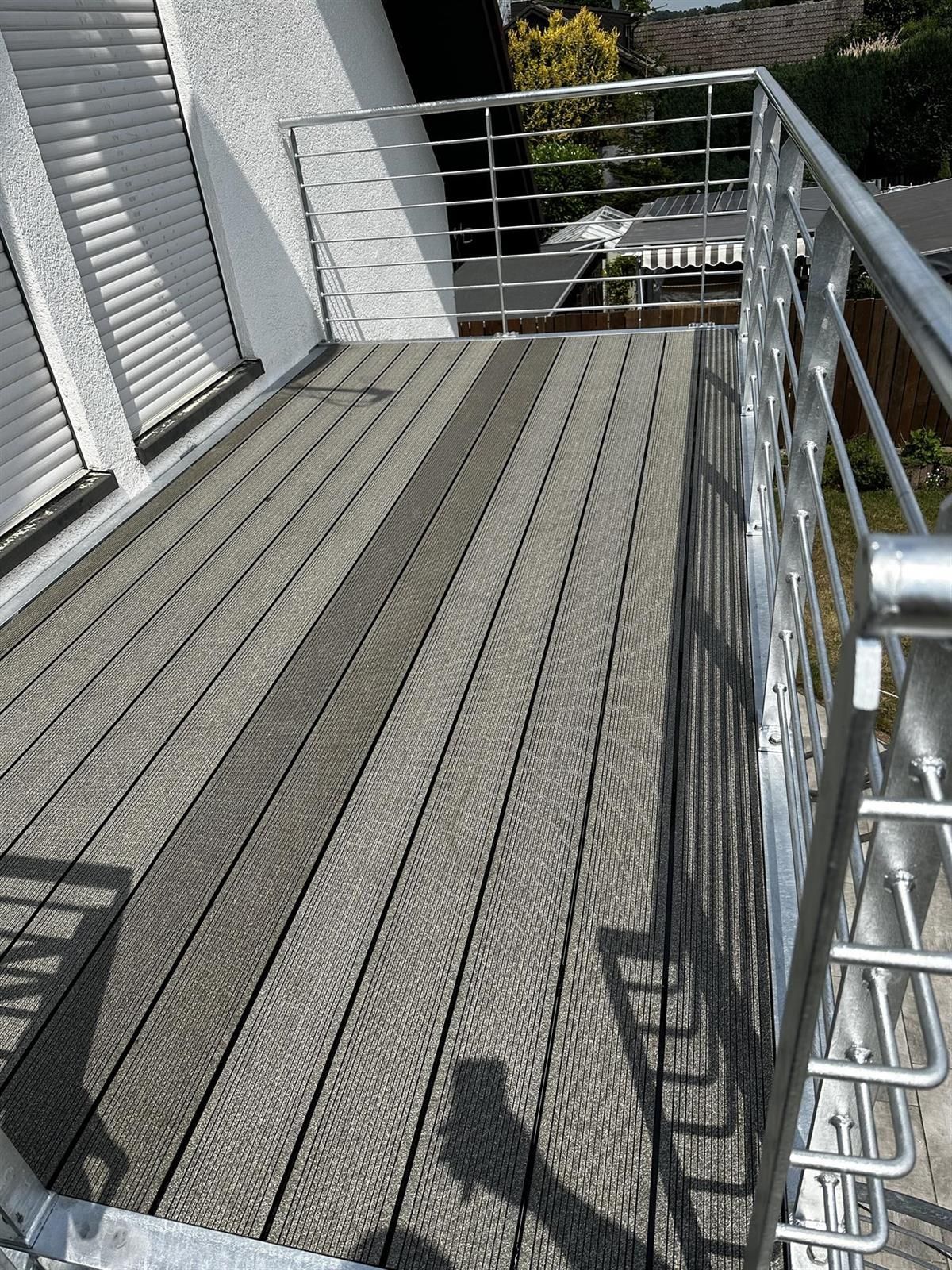 Ein Balkon mit Edelstahlgeländer und Holzterrasse