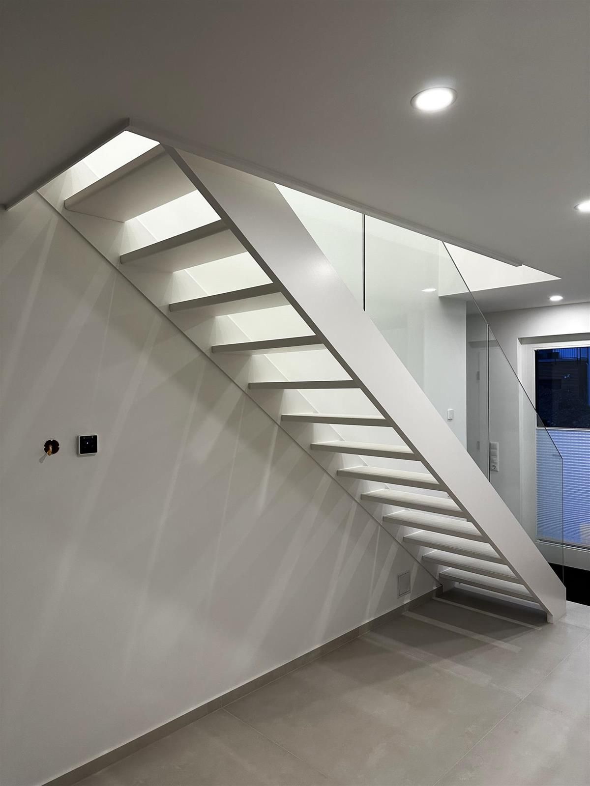 Eine weiße Treppe mit einem Glasgeländer in einem Zimmer