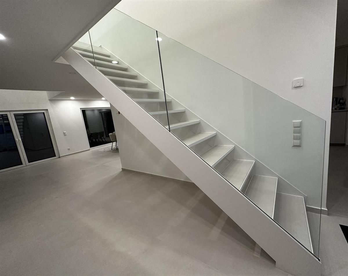 Eine weiße Treppe mit einem Glasgeländer in einem Zimmer