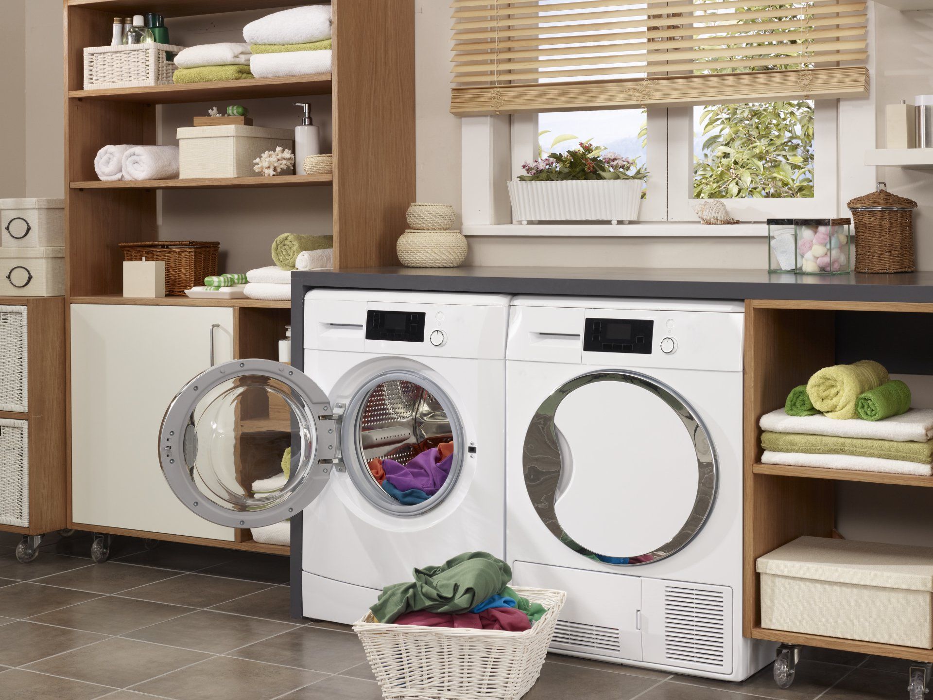 Buanderie avec porte de machine à laver ouverte, un sèche-linge, des étagères et un panier à linge