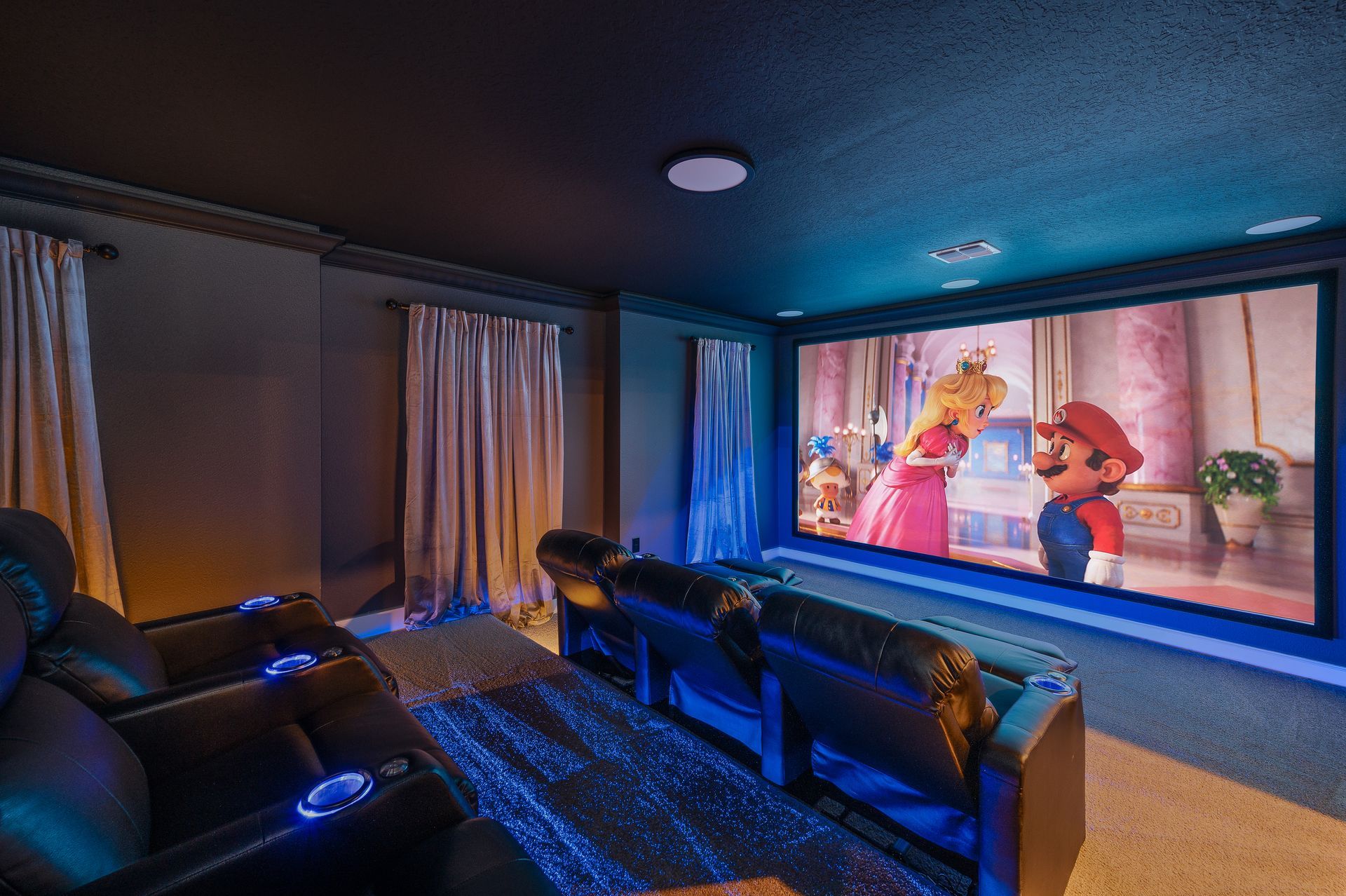 A home theater with black chairs and a large screen.