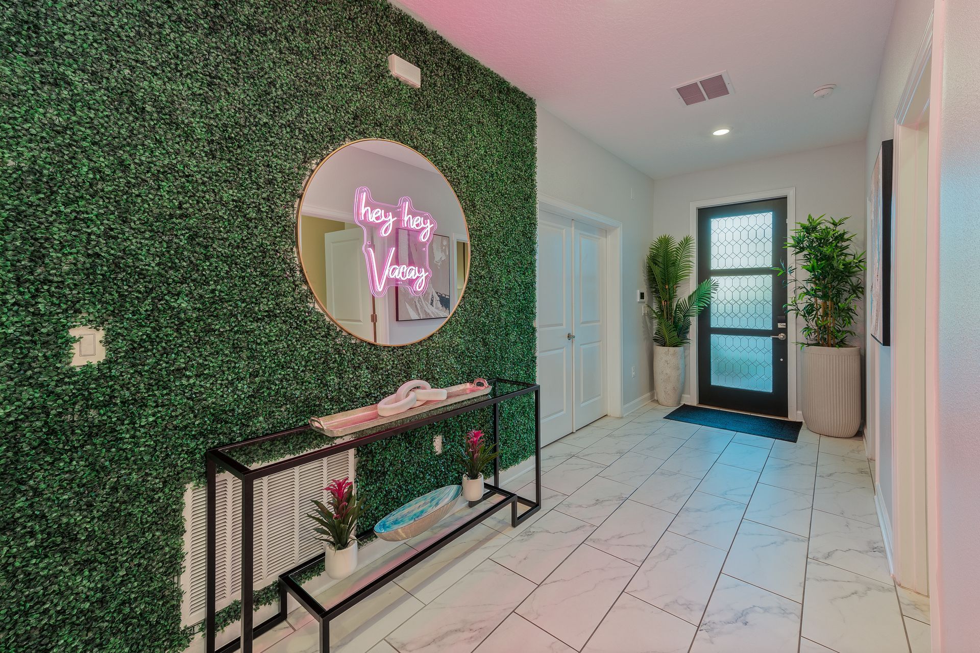 Hallway with green wall, round mirror, black door, and marble tile floors.