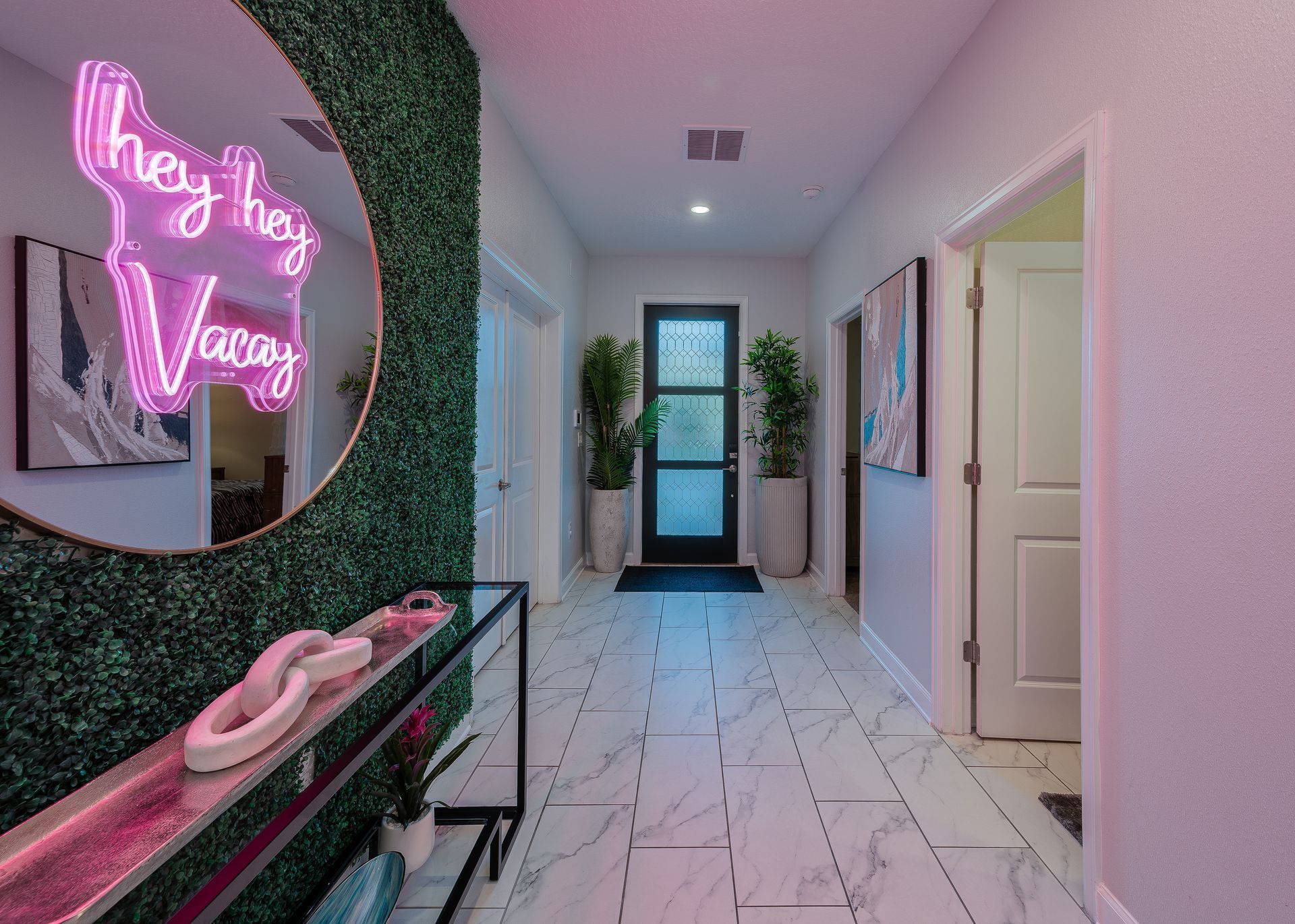 A hallway with a neon sign on the wall and a mirror.
