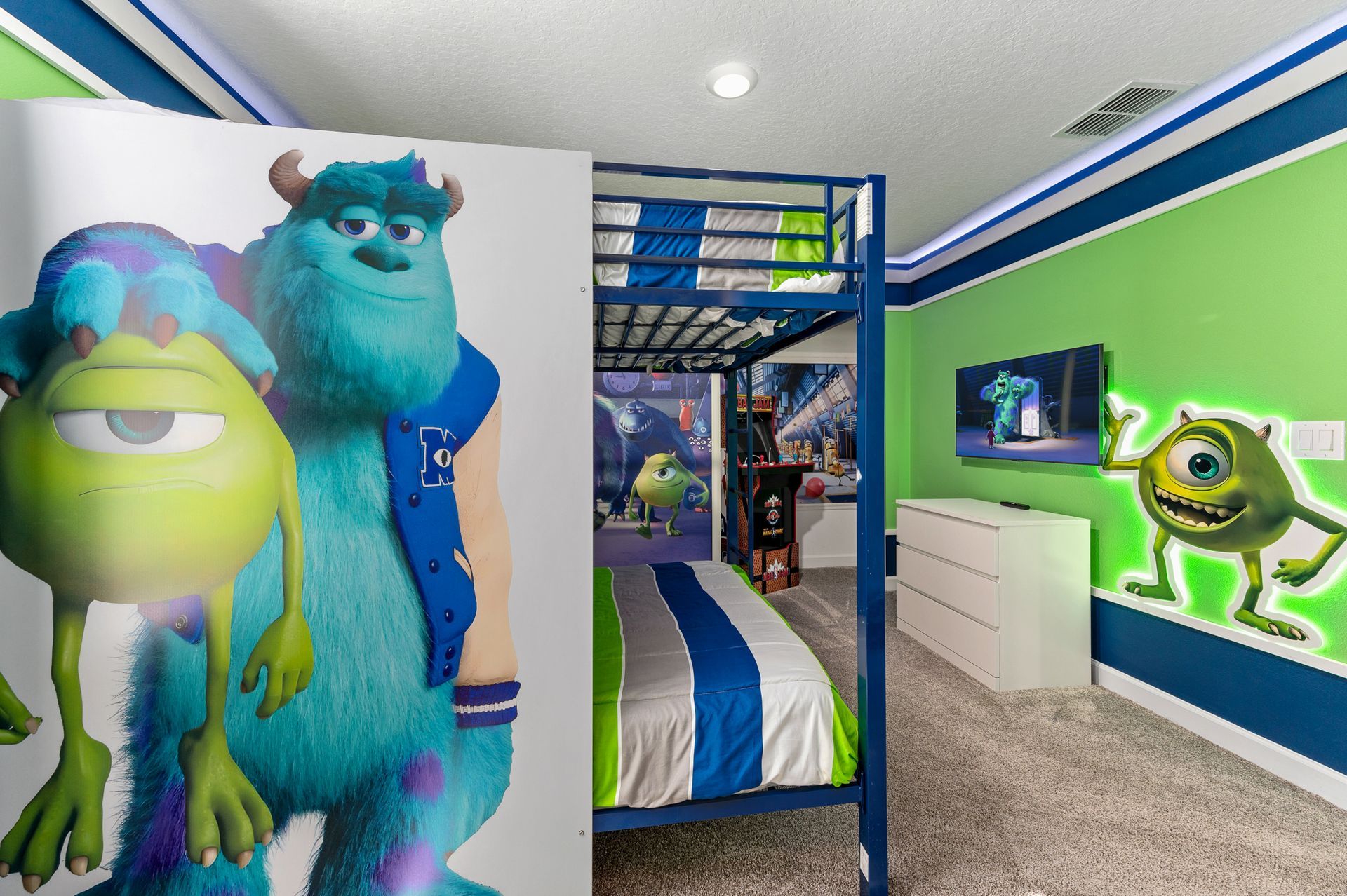 Monsters Inc. themed bedroom: Mike Wazowski and Sully on the wall, bunk beds, and a green and blue color scheme.