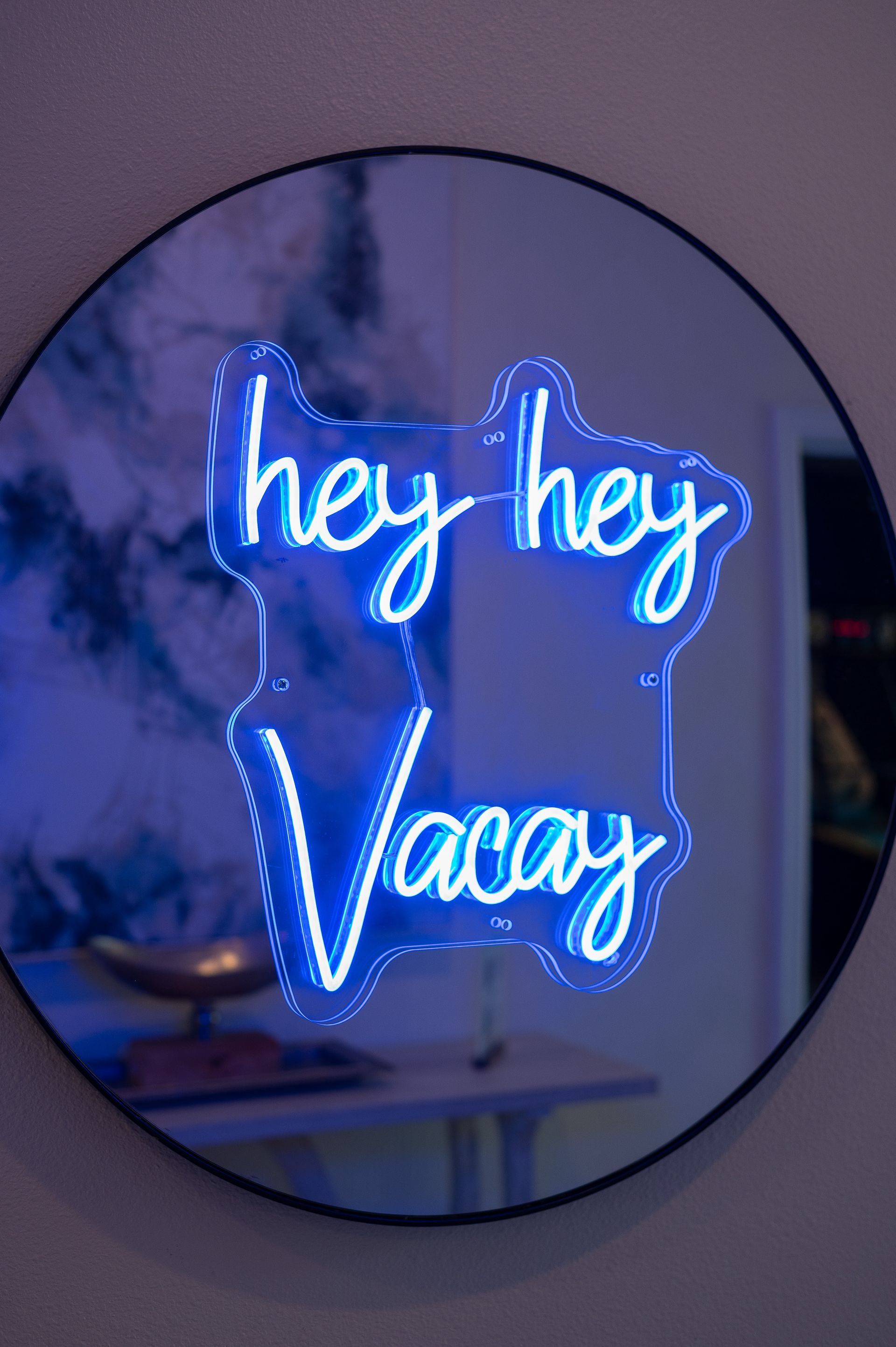 A round mirror with a neon sign that says hey hey vacay