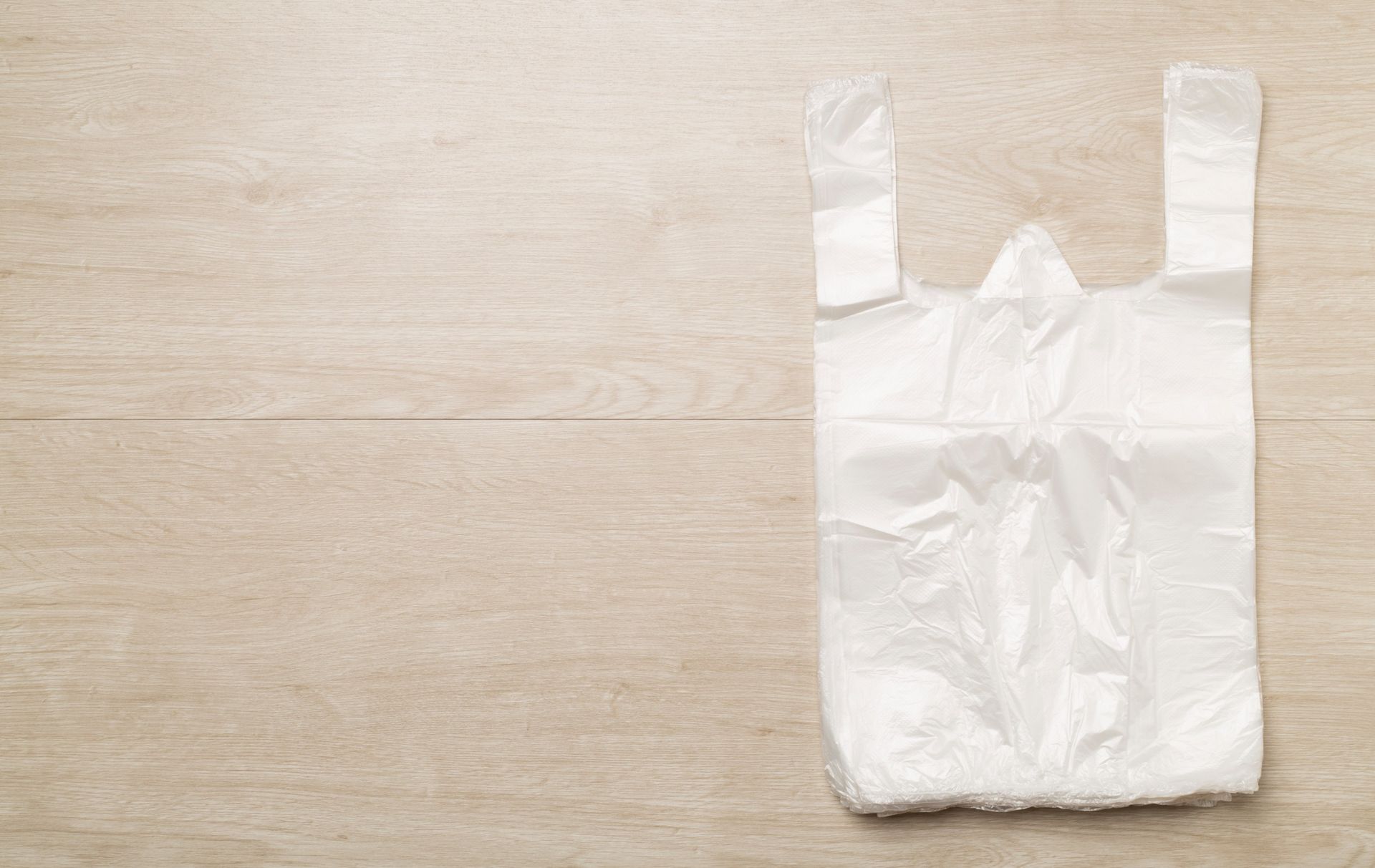 Una bolsa de plástico blanca está sobre una mesa de madera.