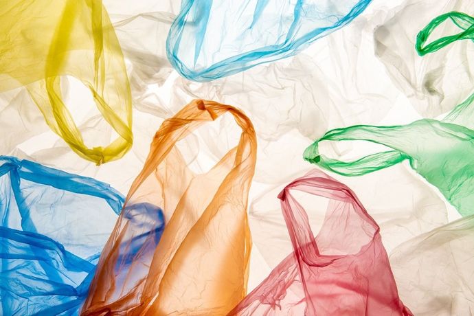 Un montón de bolsas de plástico de colores se encuentran sobre una superficie blanca.
