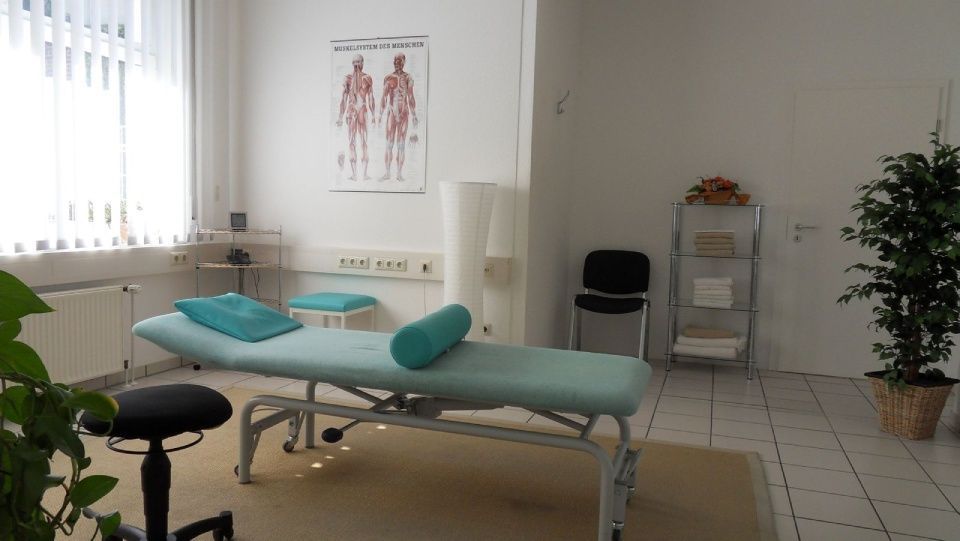 Ein Raum mit einem Massagetisch und einem Hocker