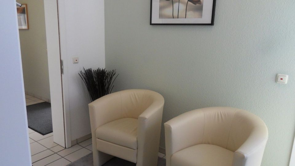 Ein Wartezimmer mit zwei Stühlen und einem Bild an der Wand.