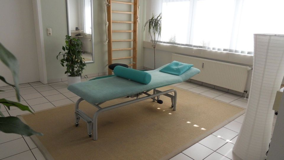 In der Mitte des Raumes steht eine Massageliege.