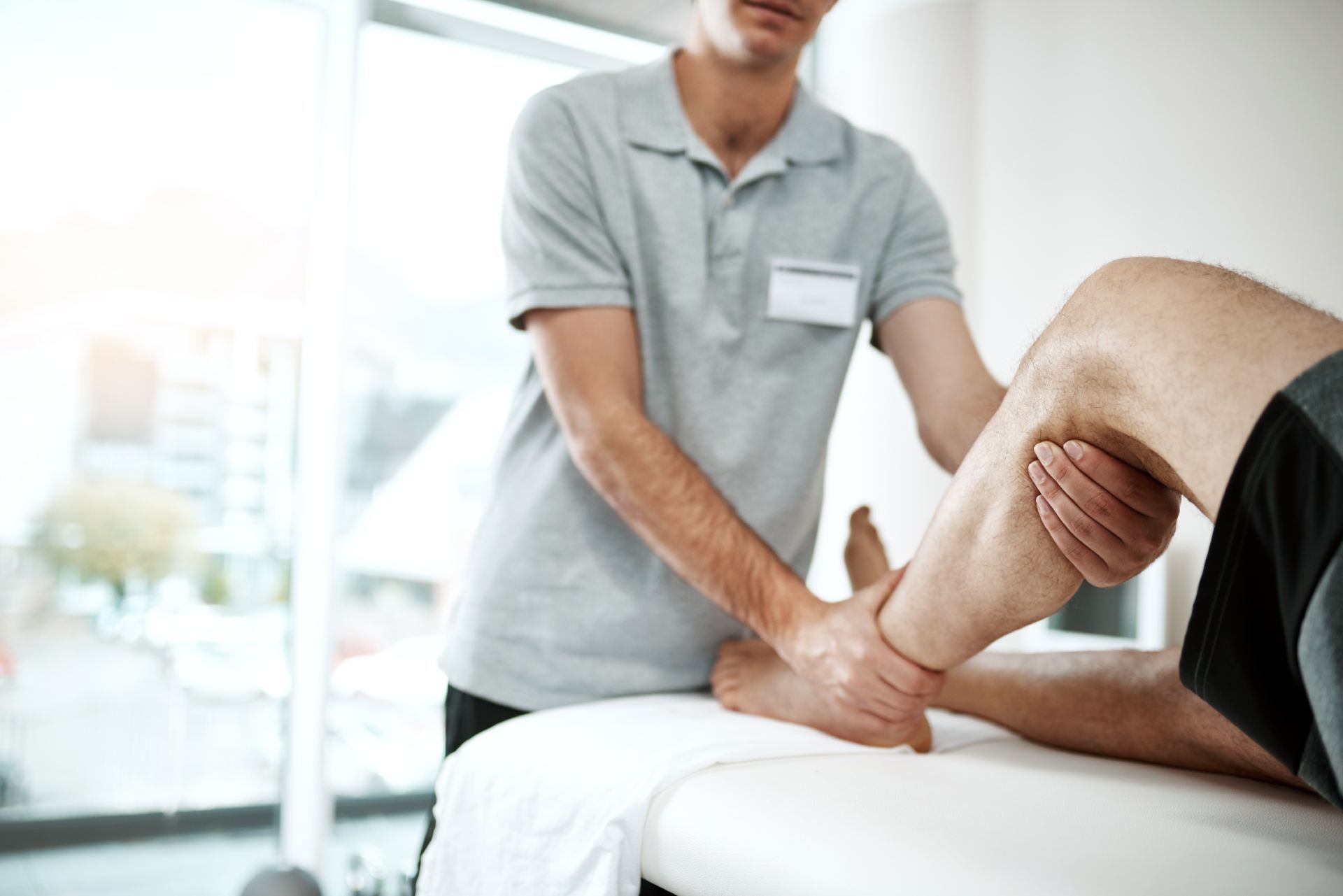Ein Mann bekommt von einem Physiotherapeuten eine Beinmassage. Aufderhöher Physiotherapie