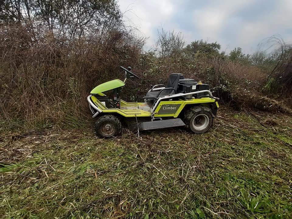 Buggy tout-terrain jaune garé sur de l'herbe boueuse près de buissons denses sous un ciel nuageux