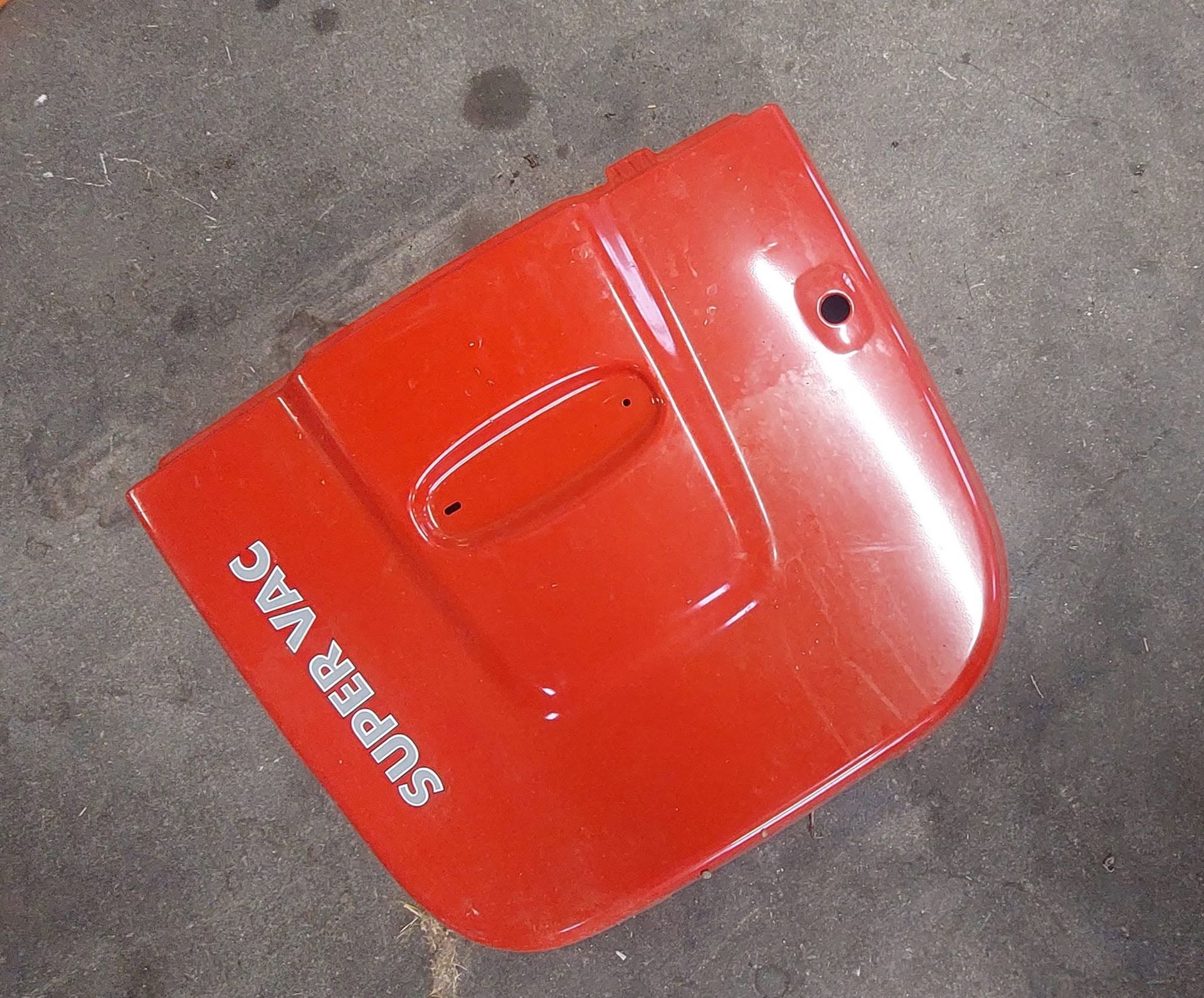 Panneau de capot de voiture en plastique rouge avec inscription blanche « SUPER RAC » sur un sol en béton.