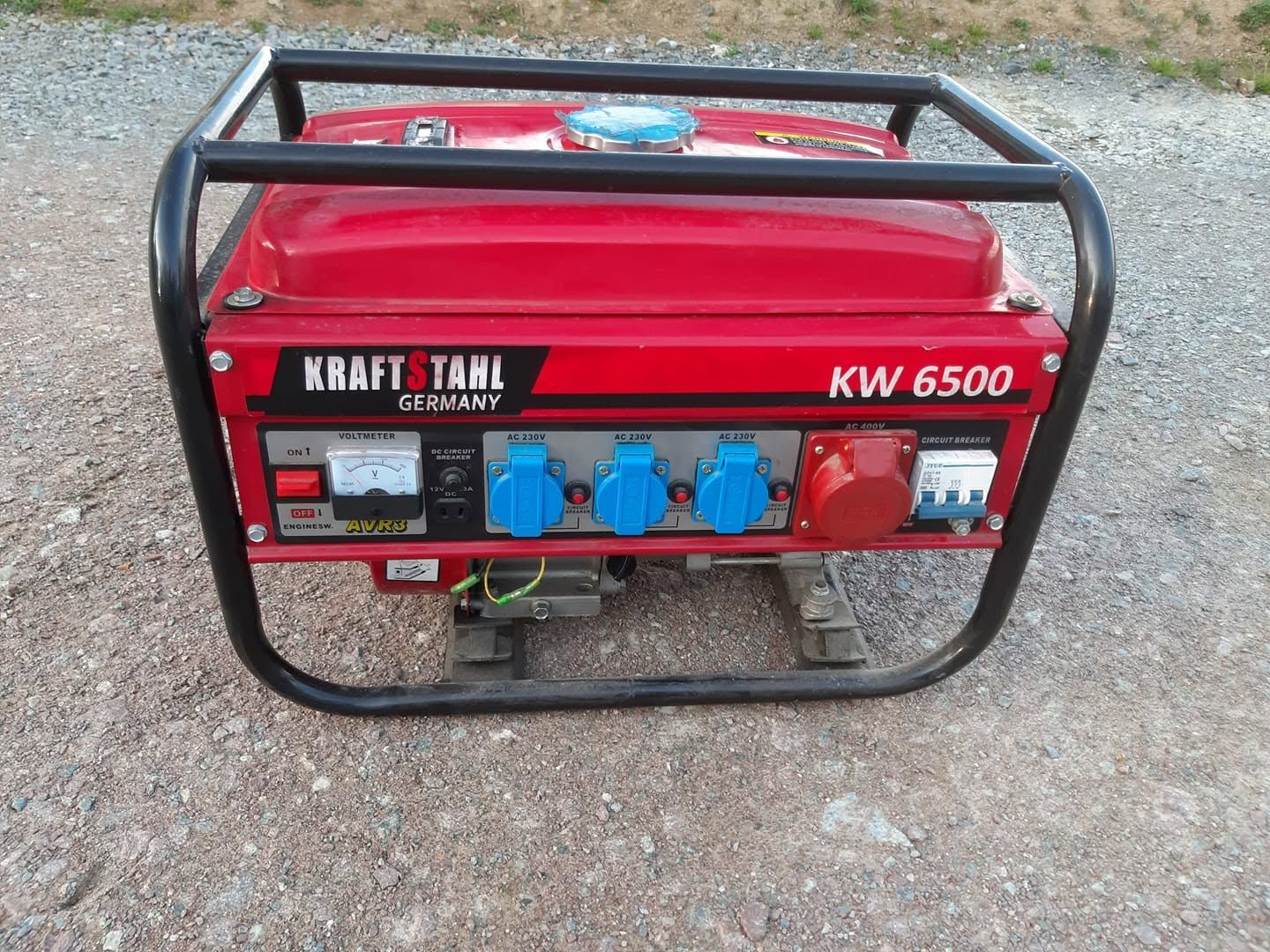 Générateur portable KRAFT TAHL KW 6500 rouge avec prises bleues sur une surface gravillonnée