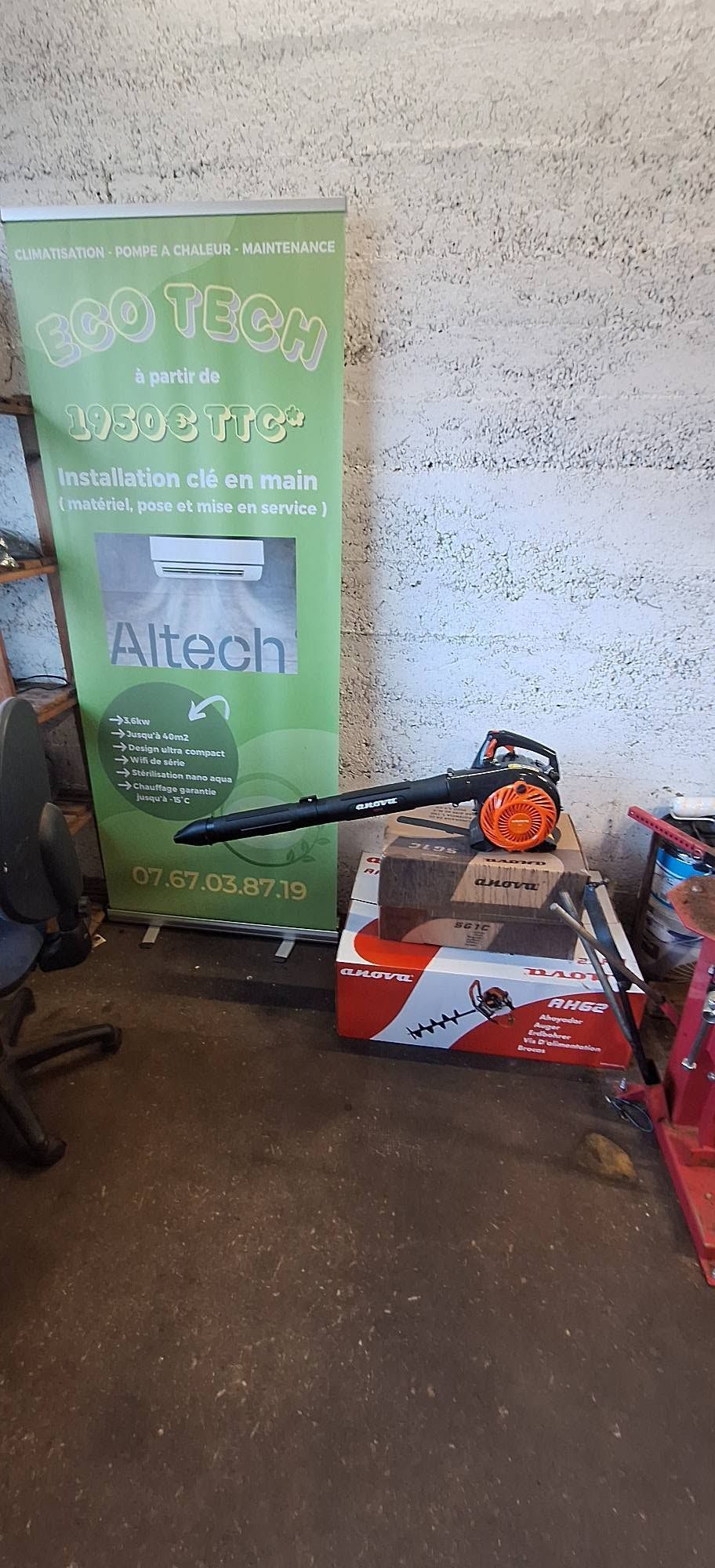 Une bannière verte Altech à côté d'un souffleur de feuilles et d'autres équipements sur un sol en béton à l'intérieur d'un garage.