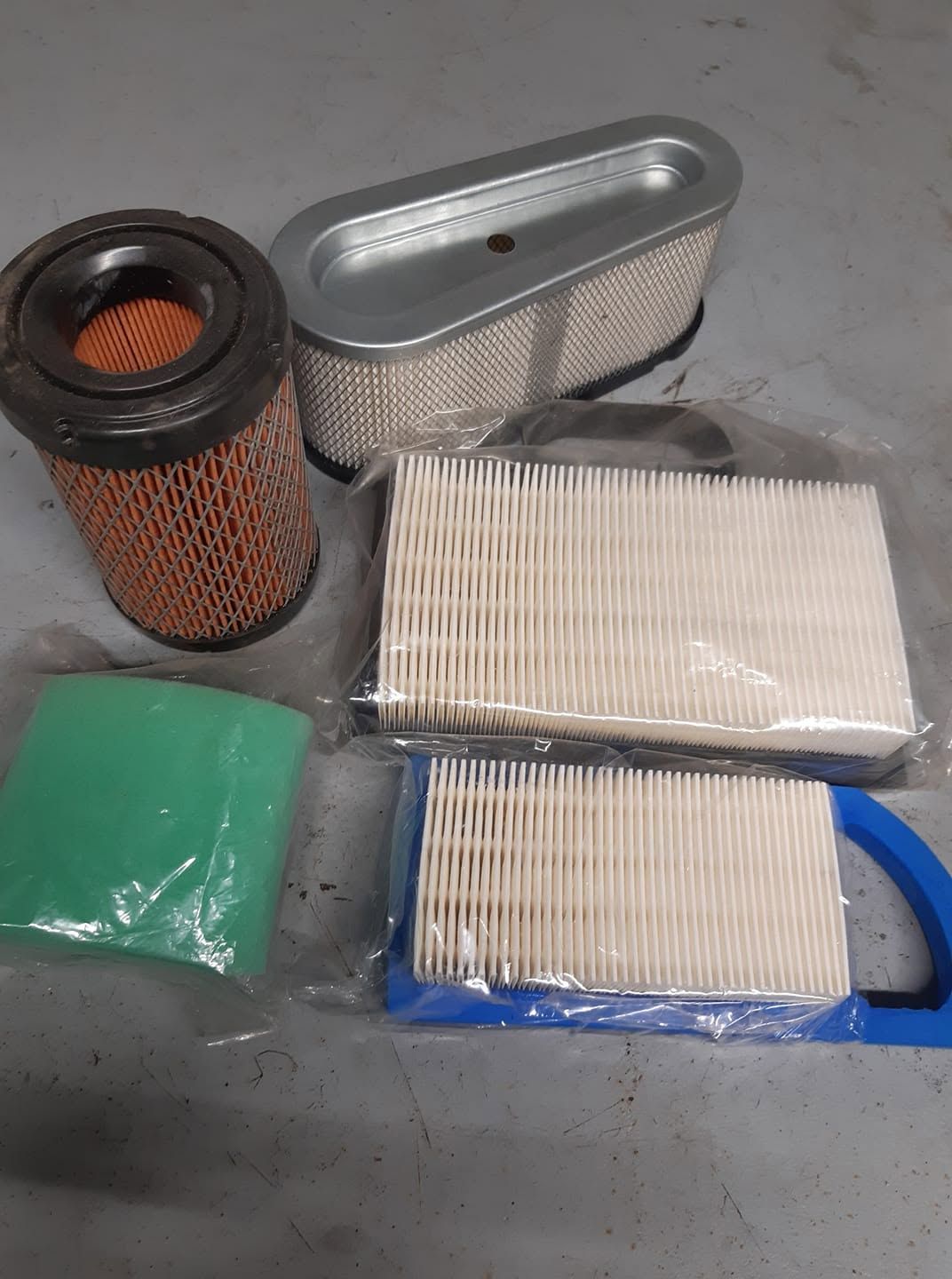 Filtres à air automobiles et sac filtrant vert posés sur une surface grise.