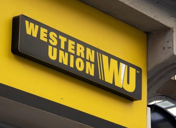 Letrero de Western Union, amarillo y negro, montado sobre una pared amarilla.