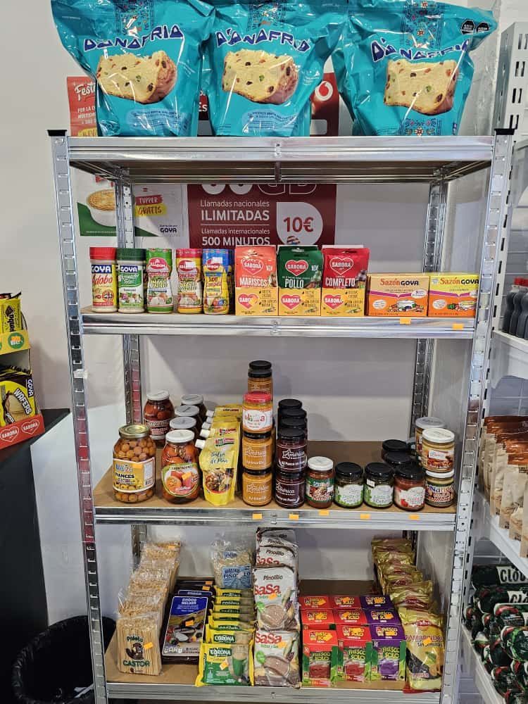 Estanterías con diversos productos alimenticios en una tienda: bolsas de pan de pasas, especias, salsa para pasta, conservas y cajas.