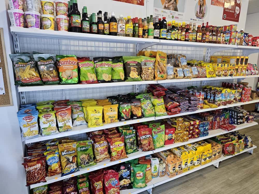 Estanterías repletas de diversos aperitivos y salsas envasados ​​dentro de una tienda.