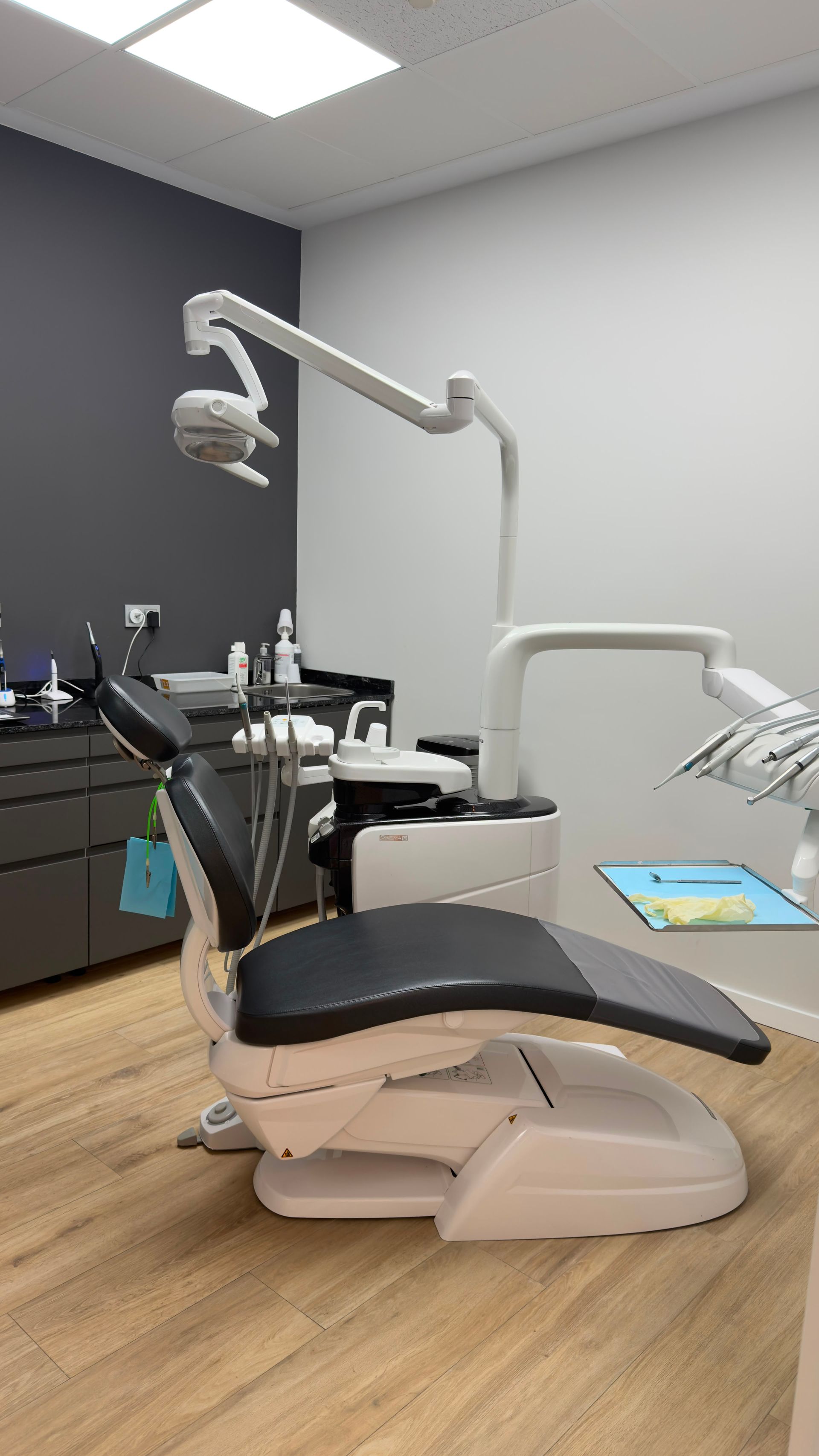 Máquina de rayos X dental con soporte para la barbilla del paciente y tubos azules sobre un fondo blanco de la clínica.