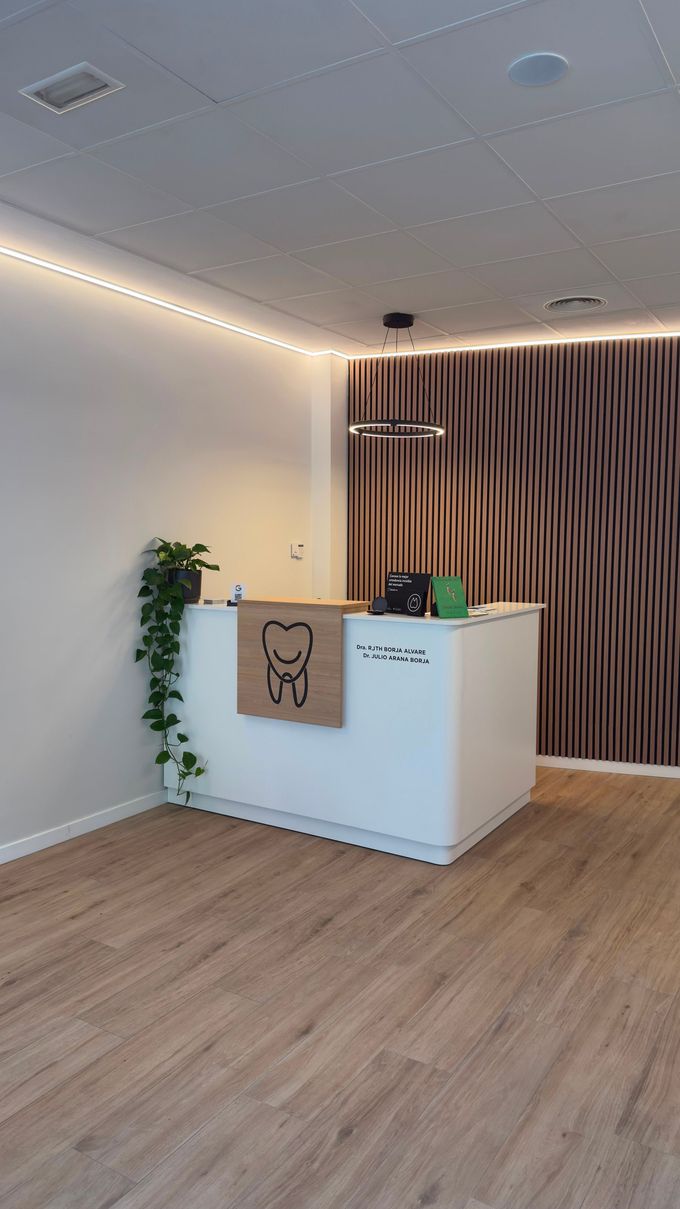 Sala de espera de una clínica dental con sillas a rayas, pared azul y mural de dientes en la pared del fondo.