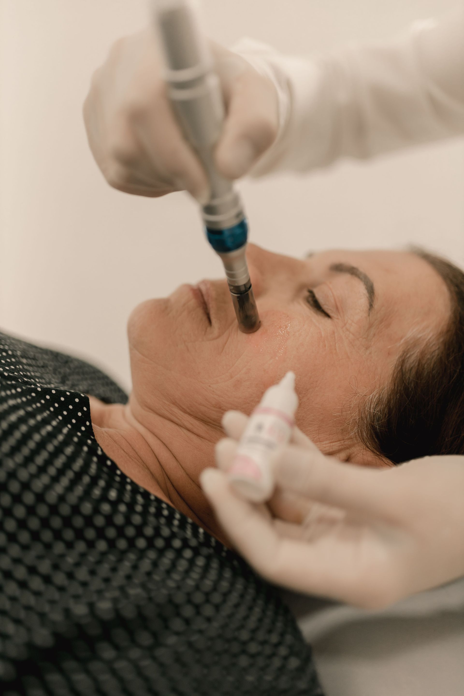 Tratamiento facial cosmético con un dispositivo aplicado a la nariz de una mujer mientras yace en una cama.