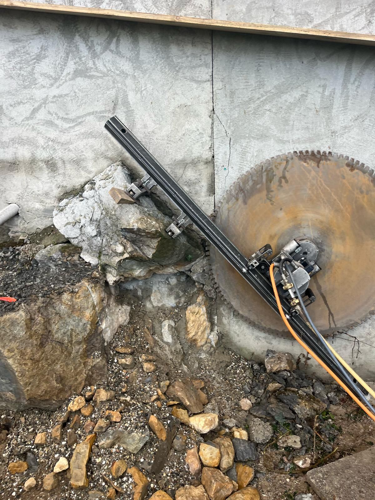 Une grande scie à béton coupant dans un mur de fondation en pierre sur un chantier de construction.