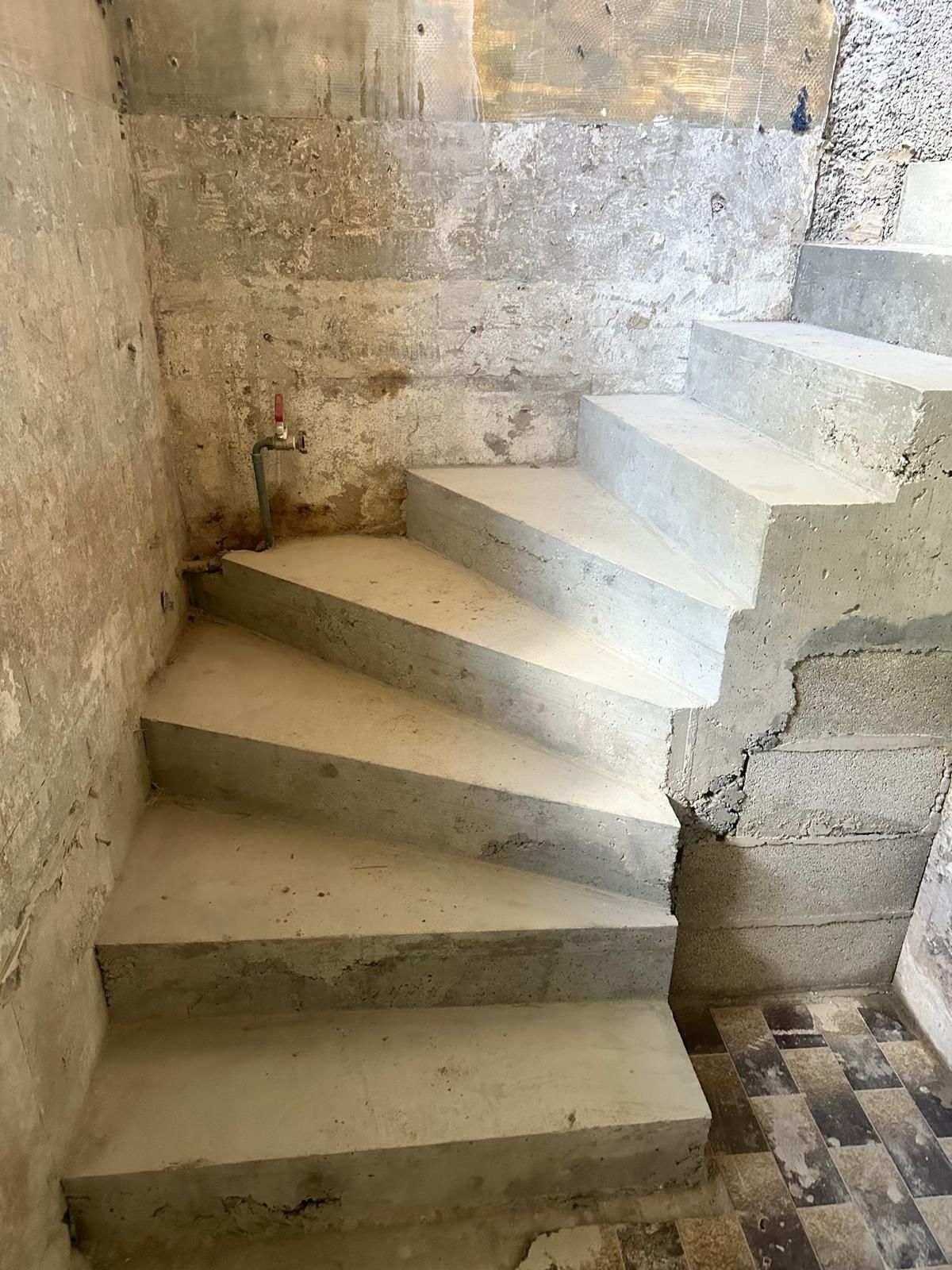 Escalier en béton en colimaçon dans un bâtiment vieilli et patiné.