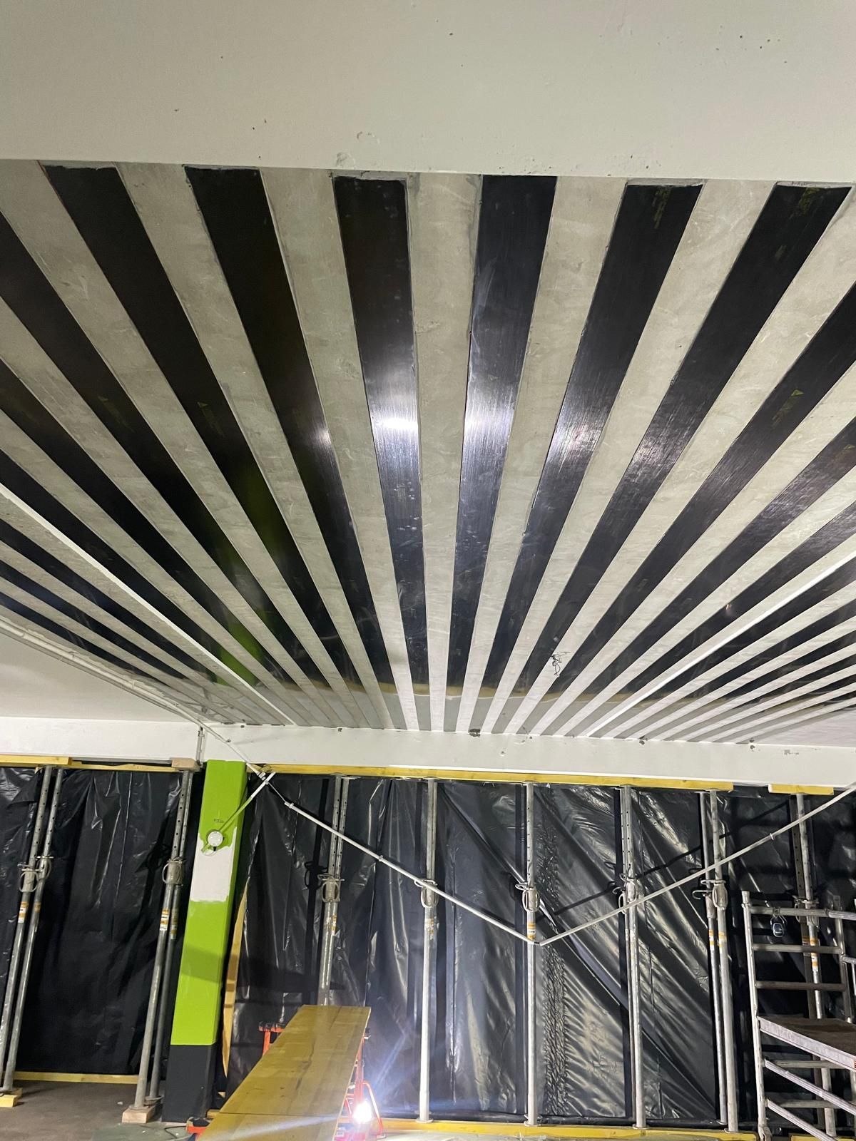 Renfort de plafond rayé noir et gris dans un espace commercial.