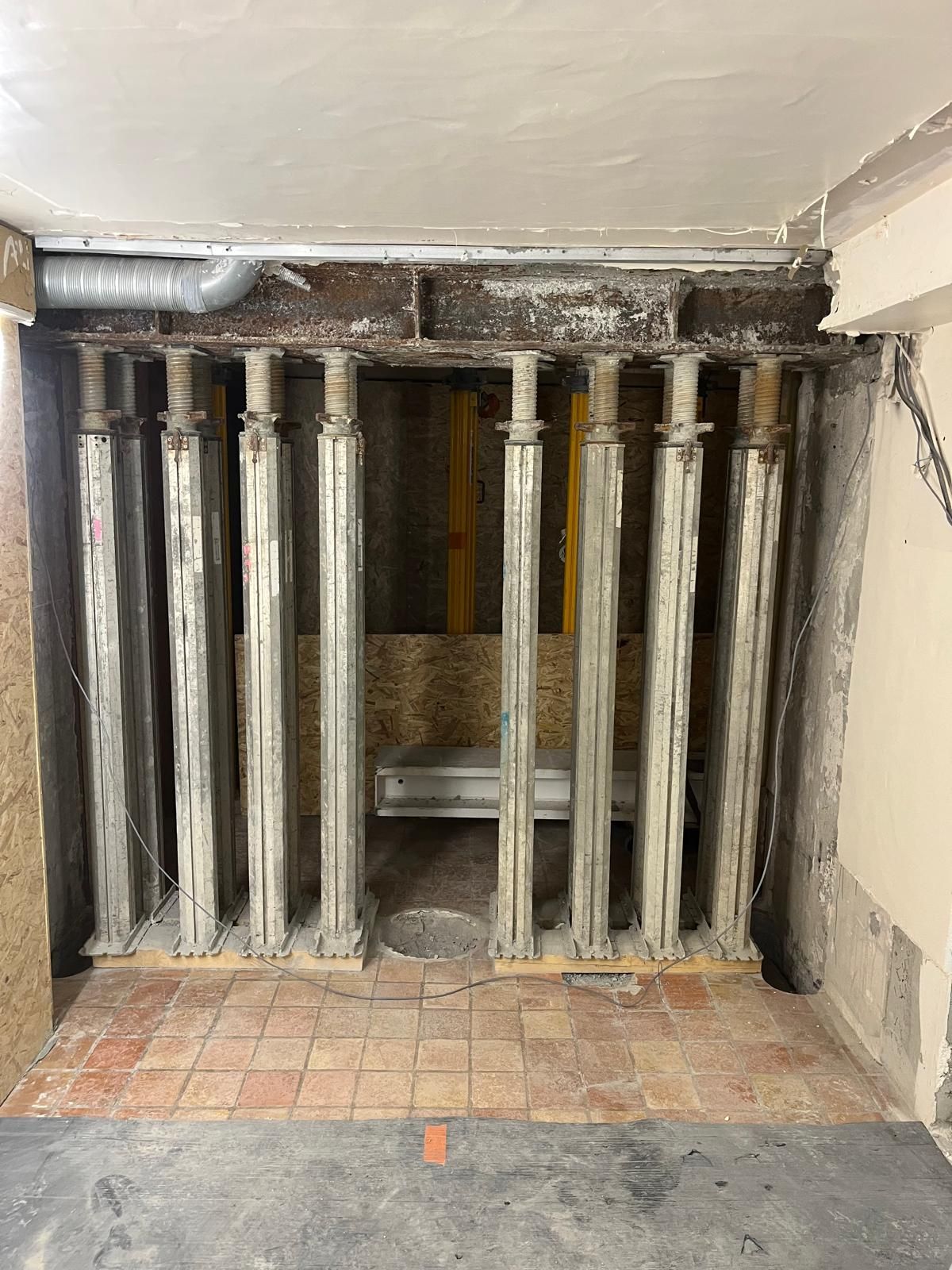 Supports soutenant un plafond. Des poutres métalliques et des planches de bois soutiennent le plafond.