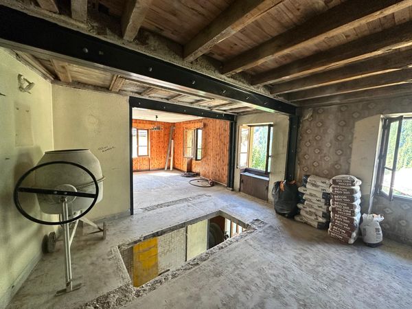 Un camion équipé d'une grue déployée travaille près d'un bâtiment. Cônes orange, montagnes en arrière-plan.