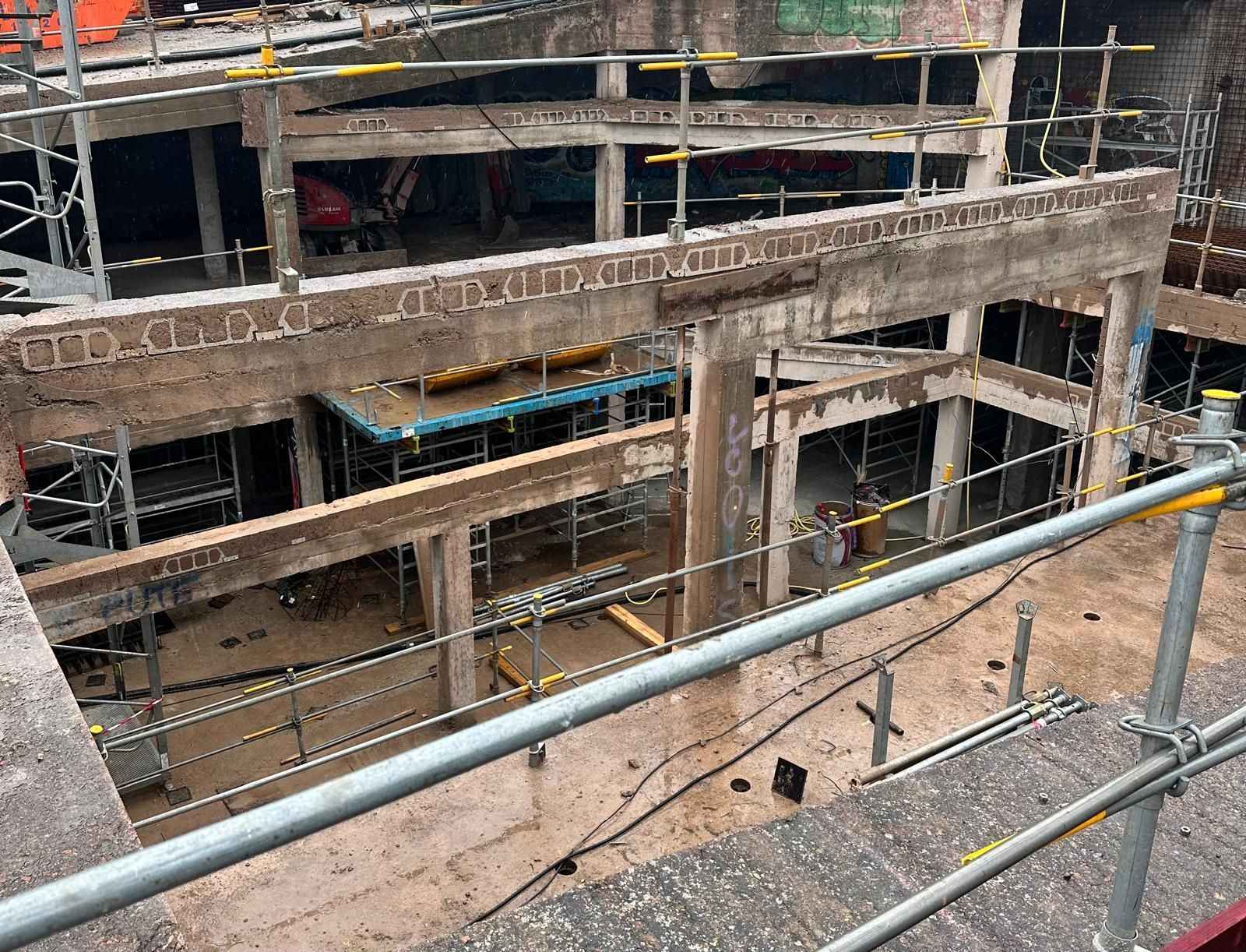 Bâtiment de deux étages en briques et stuc blanc partiellement démoli. Des débris jonchent le sol.