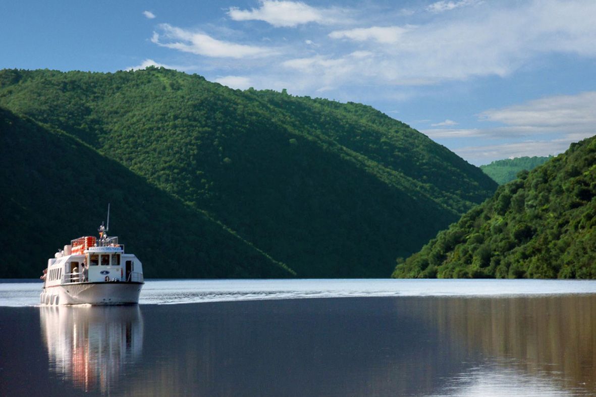 Un barco flota en un lago con montañas al fondo.