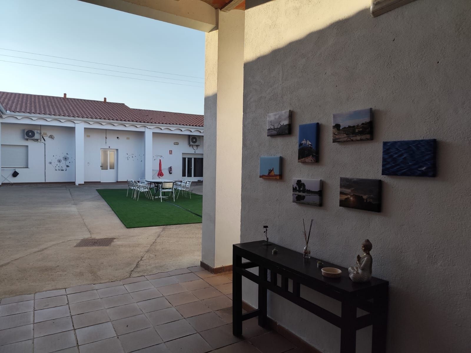 Un patio con una mesa y cuadros en la pared.
