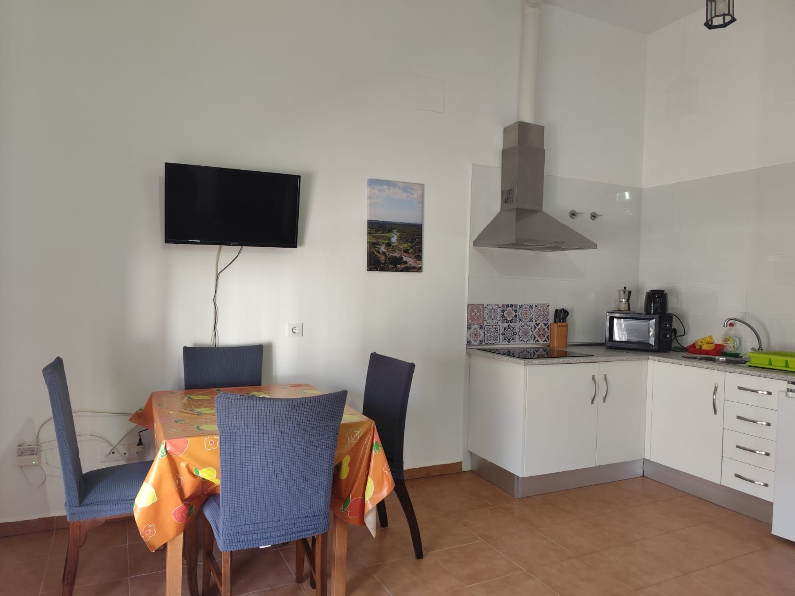 Una cocina con mesa y sillas y un televisor de pantalla plana.